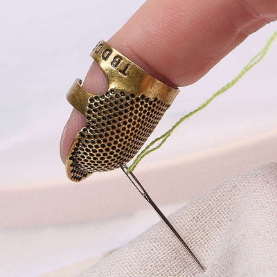 Close-up of a hand wearing a thicken adjustable finger thimble sewing needle holder on the thumb while stitching fabric